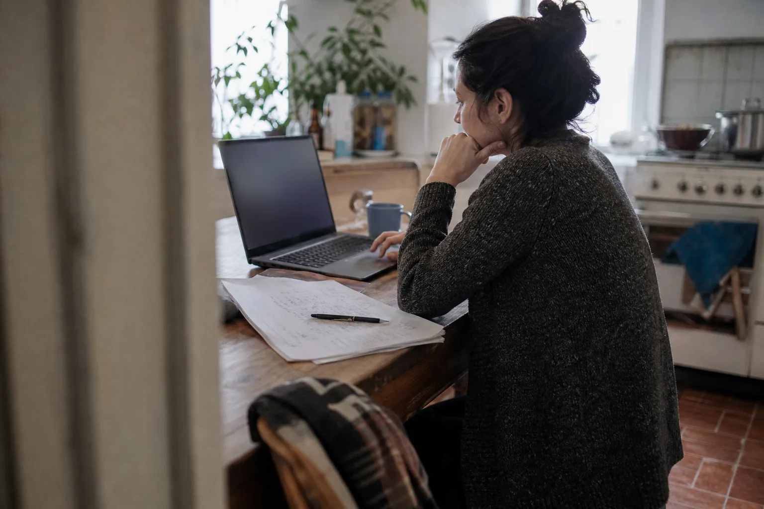 Founder reading a first draft of a services agreement on a laptop at a kitchen table