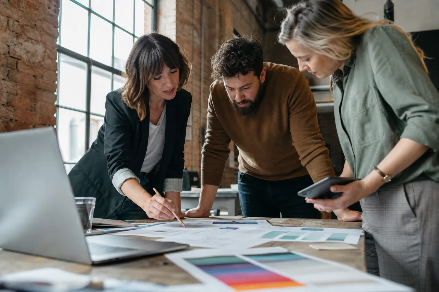 Small agency team reviewing a printed client proposal with a pricing table at a studio worktable