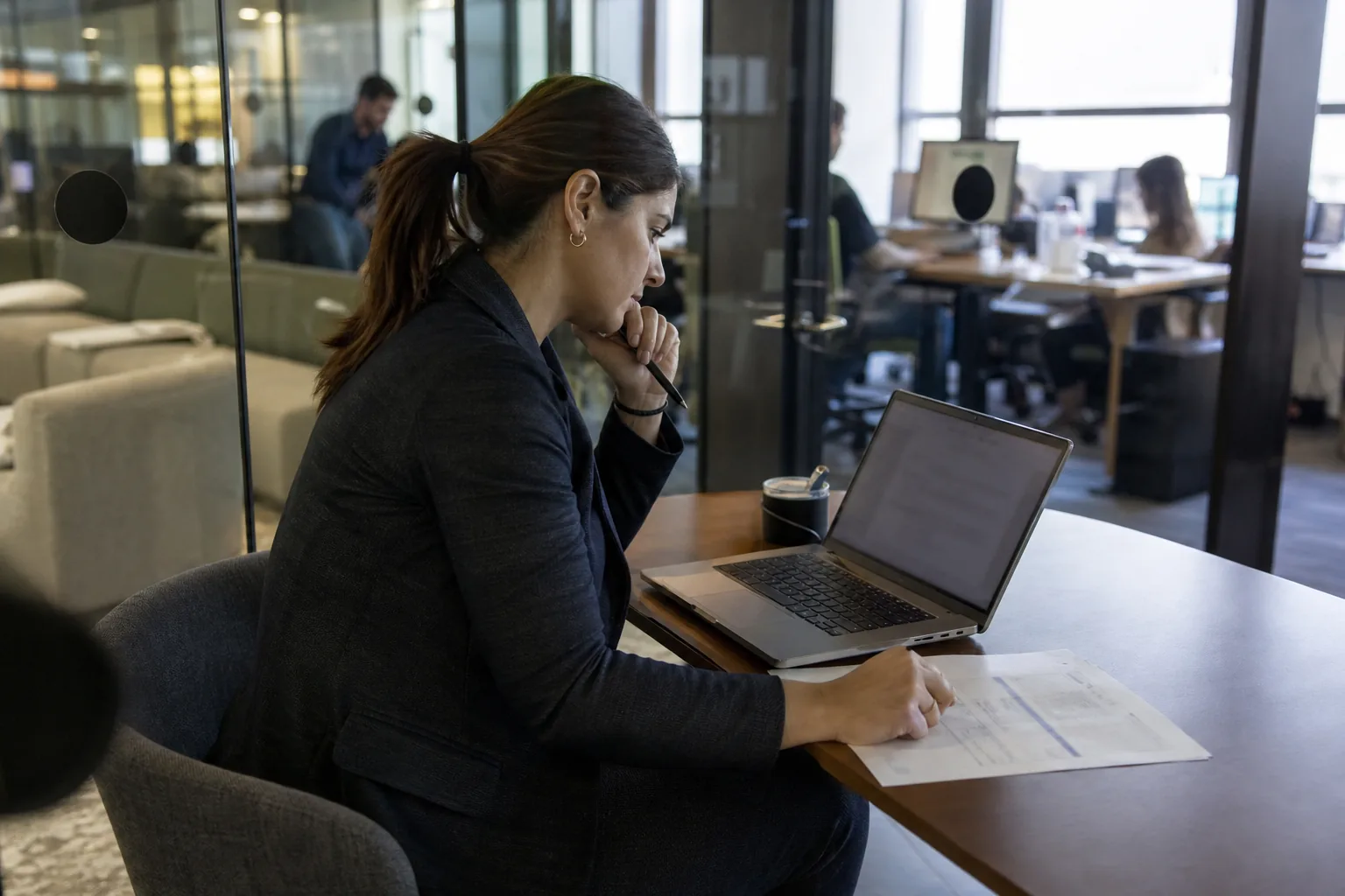 Sales operations manager comparing contract tools on a laptop in a glass walled meeting room