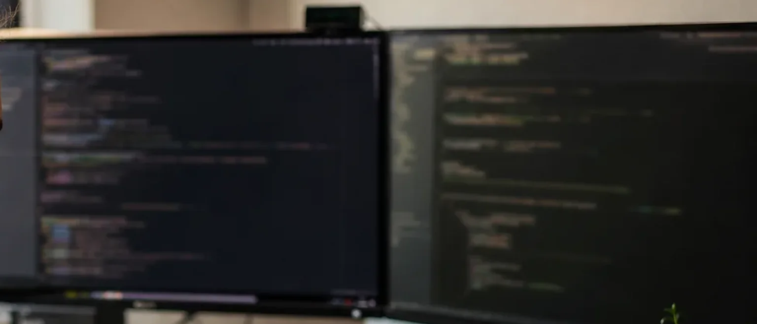 Two monitors showing webhook handler code on a developer desk