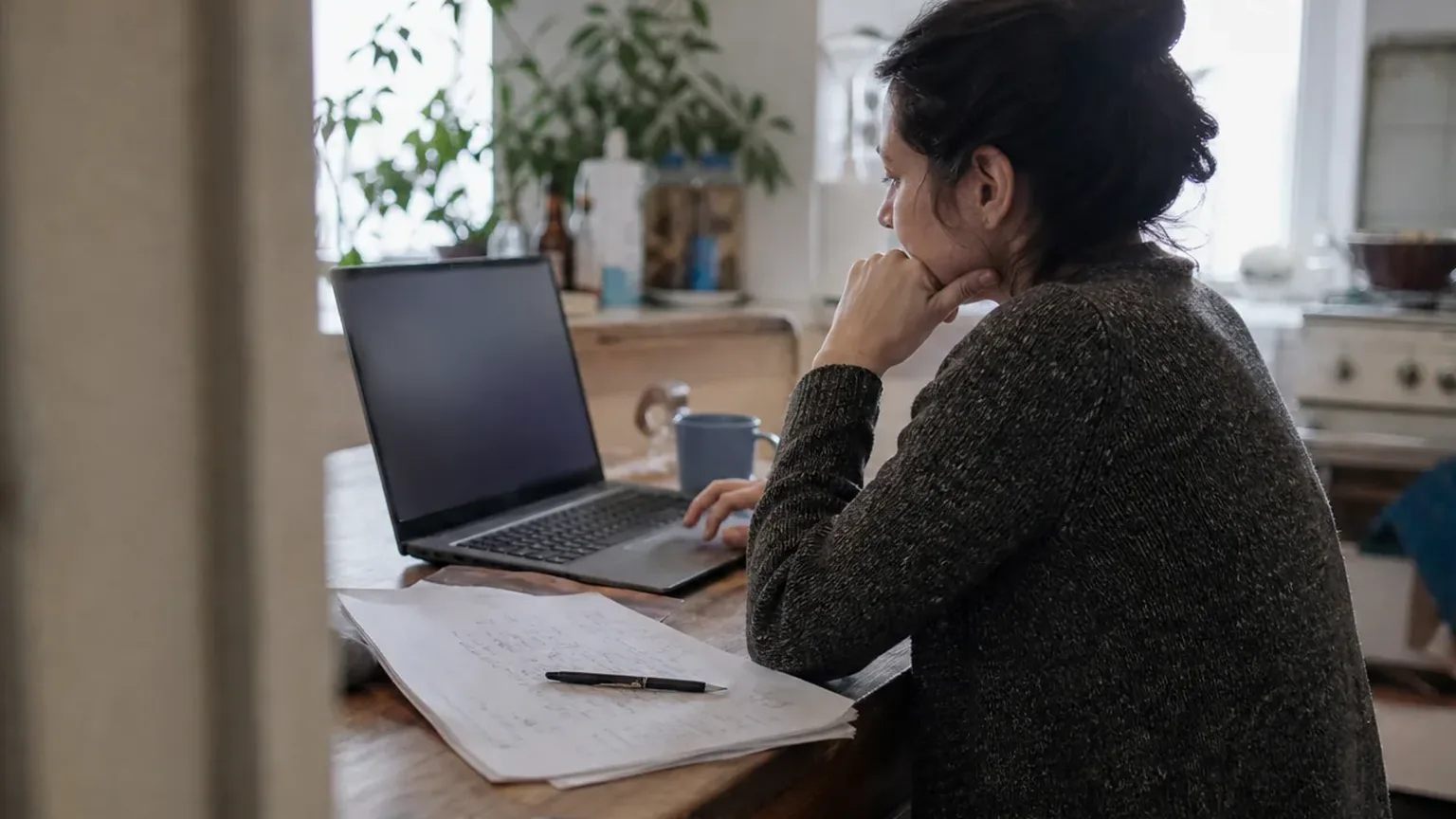Account executive preparing a proposal on her laptop at a kitchen table