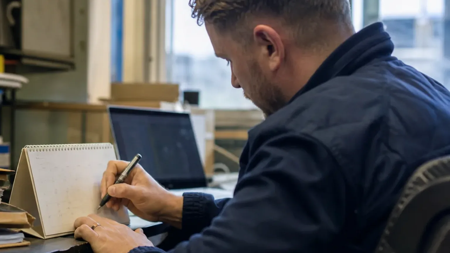 Reviewer writing margin notes on a contract draft at his desk