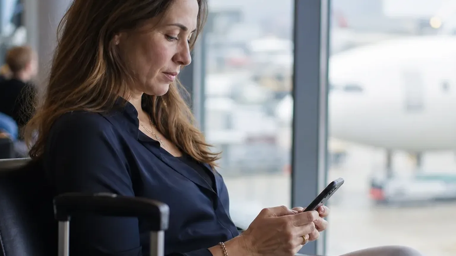 Independent consultant reading a consulting agreement on her phone in a quiet lounge